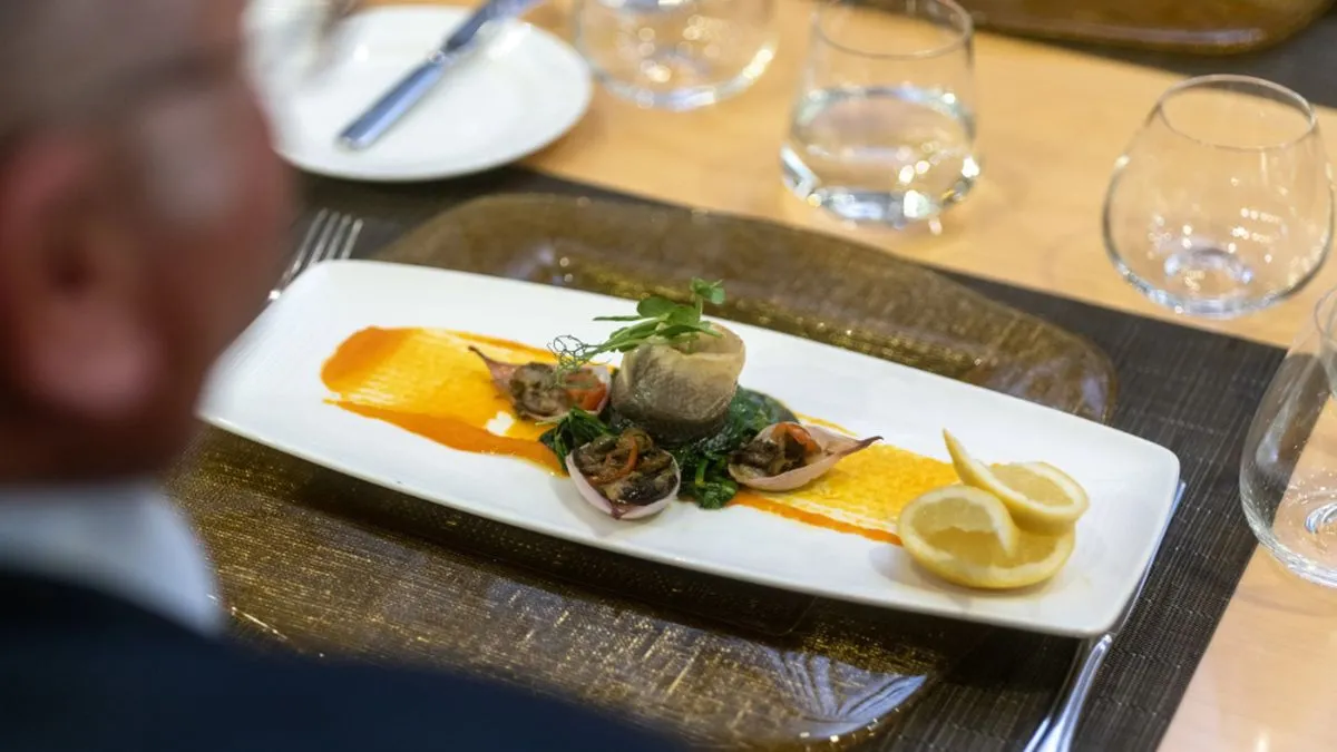 The view over a man’s shoulder of his meal on board an Ambassador Cruise