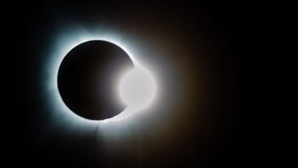 The moon moving in front of the sun during a total eclipse.