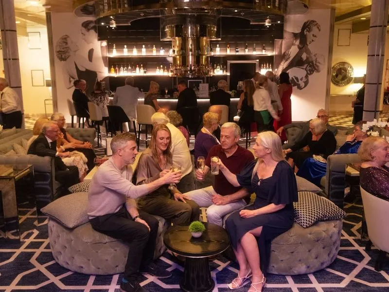A group of people sitting in a Raffles lounge bar, toasting with drinks.
